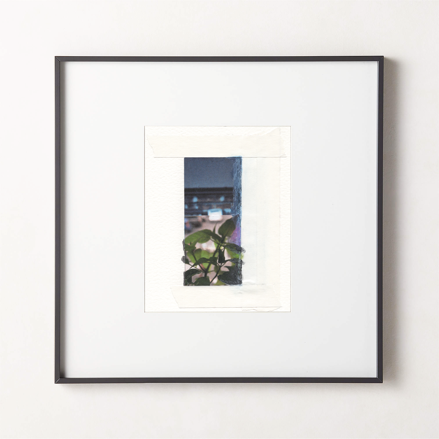 Mixed media photo collage with deep blue-gray painted surfaces, green botanical leaves, and architectural elements in a small black fame.