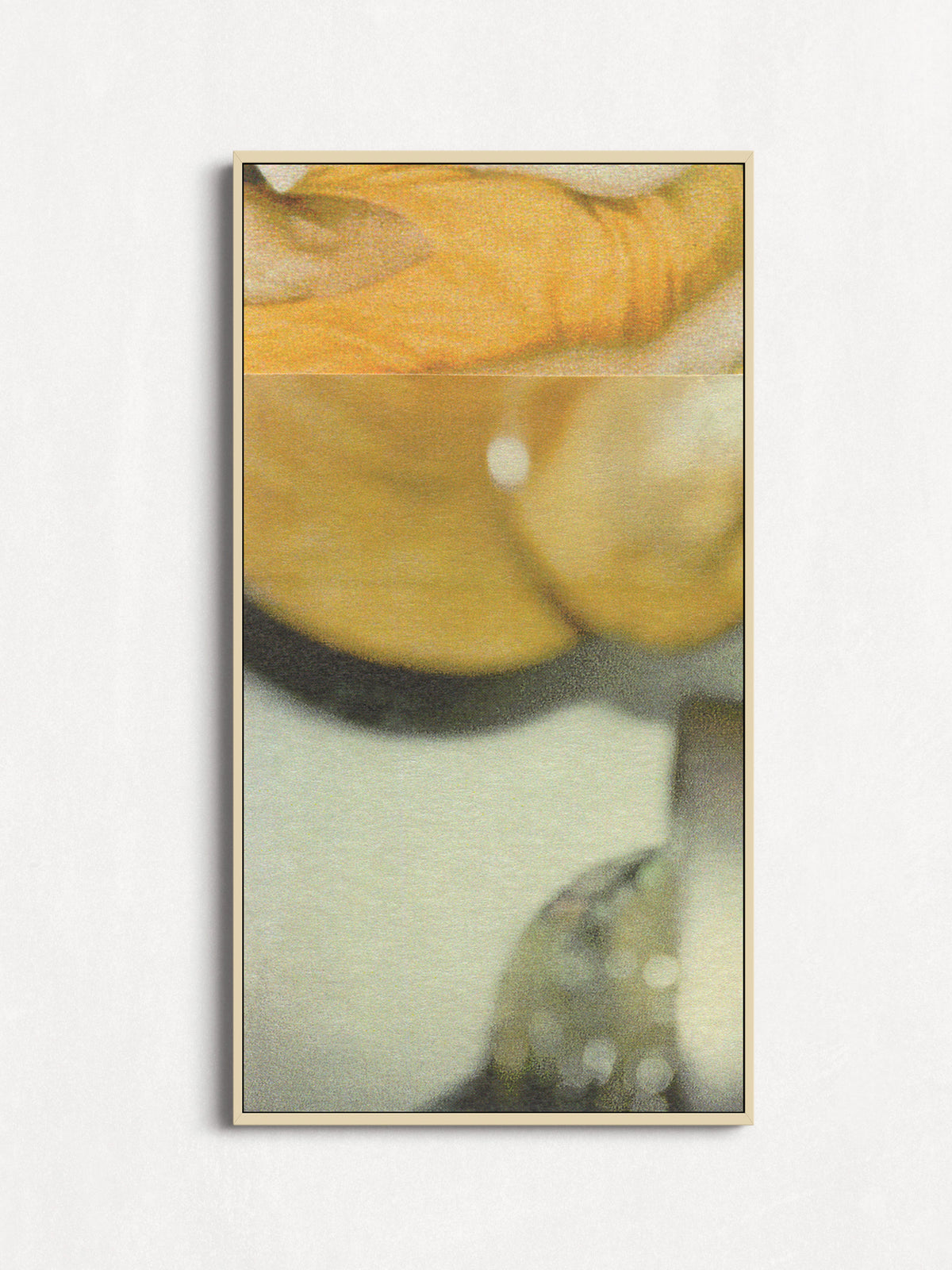 A framed abstract art print featuring soft yellow, beige, and gray tones, displayed on a clean white wall.
