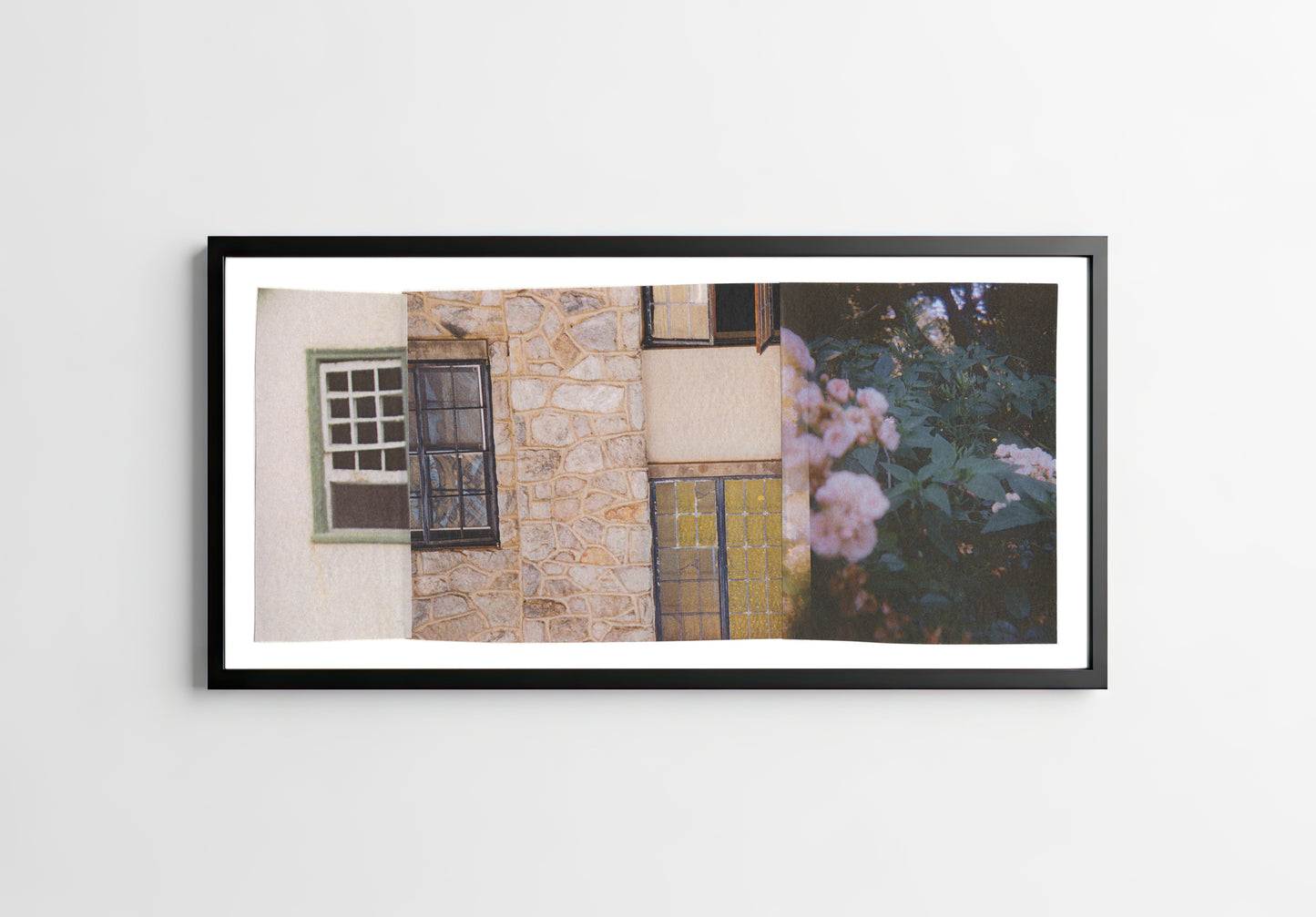 Pink, green, and cream collage of a stone wall with windows, a door, and flowers in a black frame.