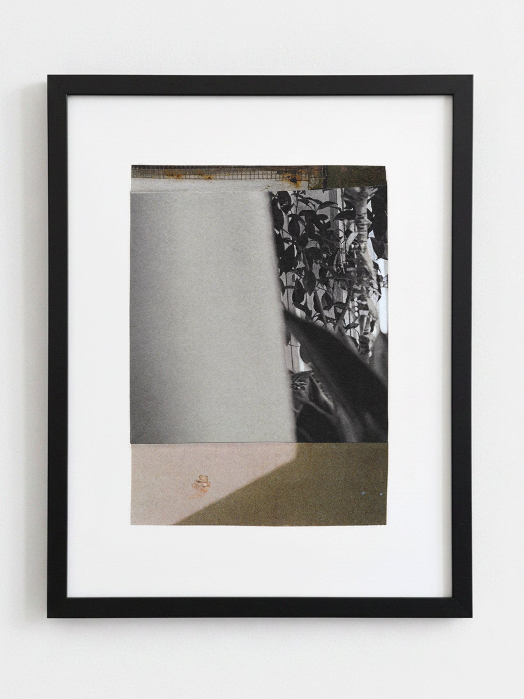 A framed abstract art print featuring a black and white collage with textured paper elements, set within a sleek black frame against a light gray wall.