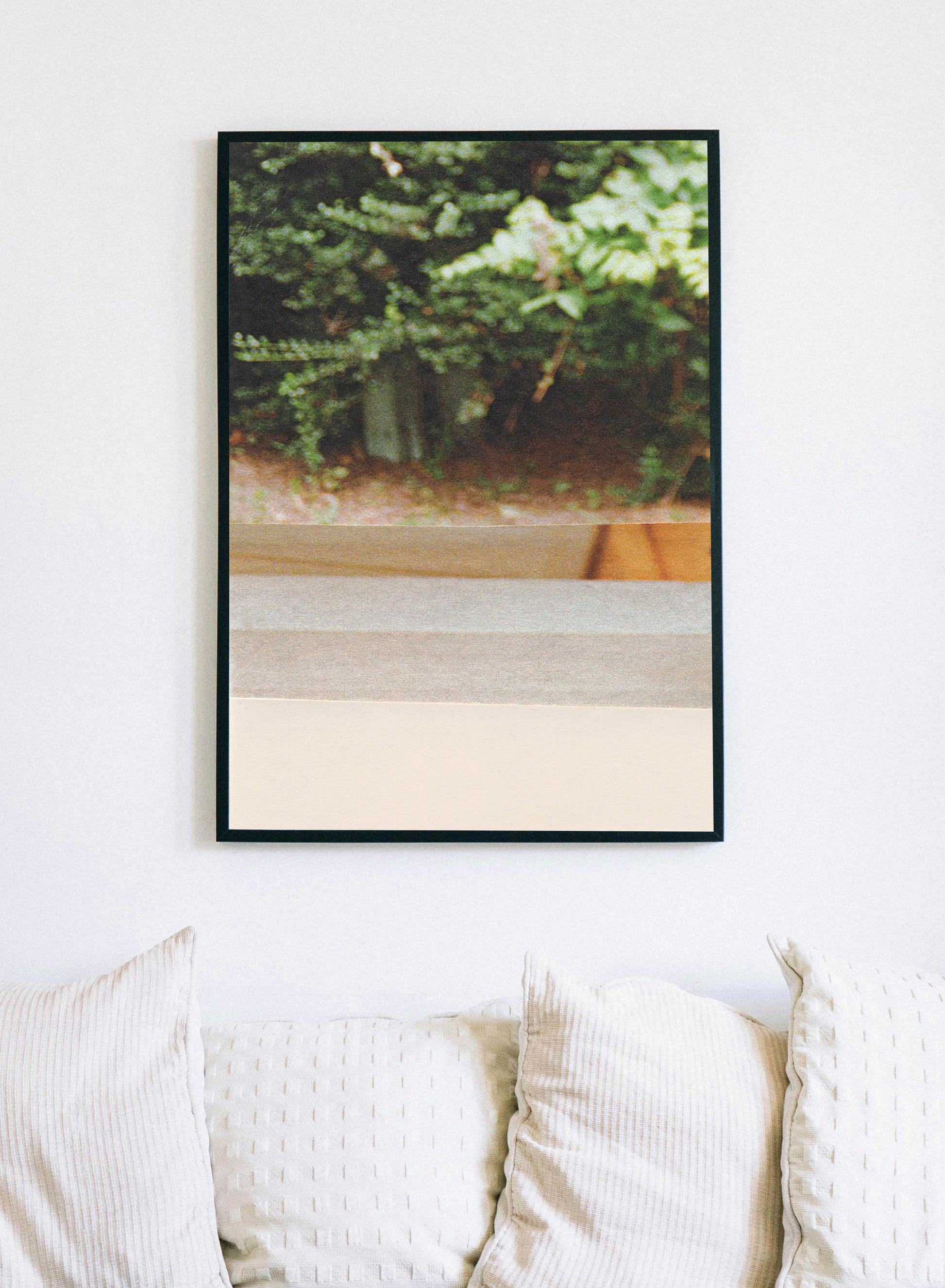 Framed photo collage with green leaves and peach accents on a wall above a sofa.