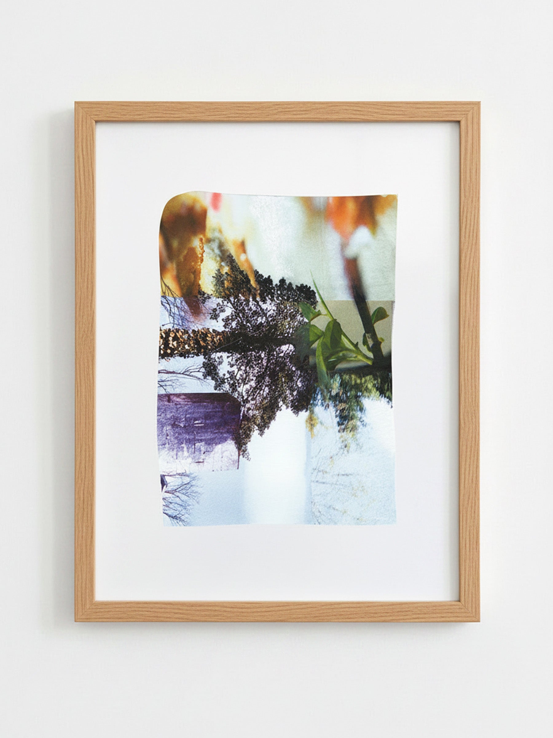 A framed abstract photographic print with a light wood frame and white mat, hanging on a plain white wall.