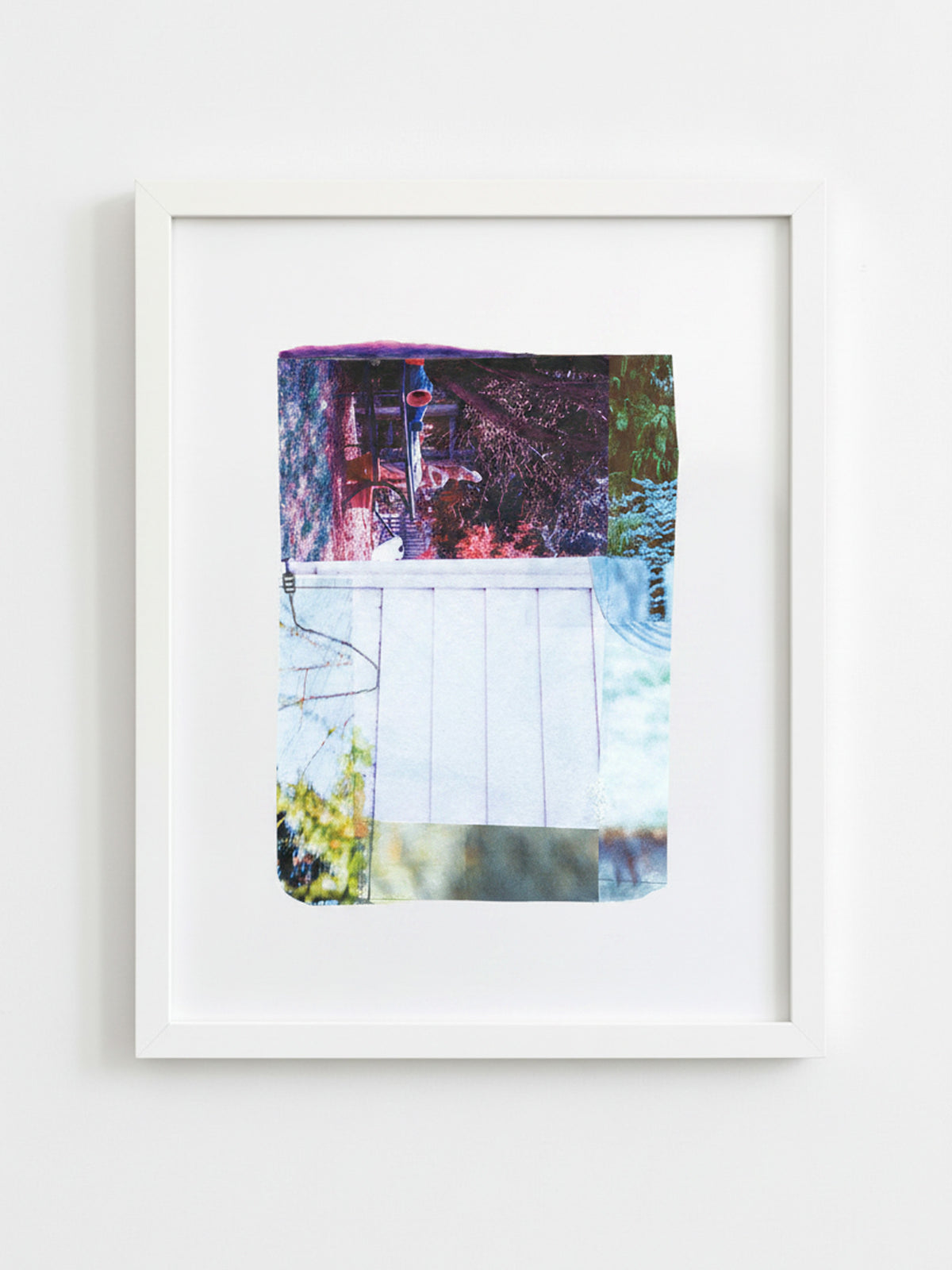A framed abstract art print featuring a colorful collage of purple, blue, green, and white tones, presented in a white frame against a light gray wall.