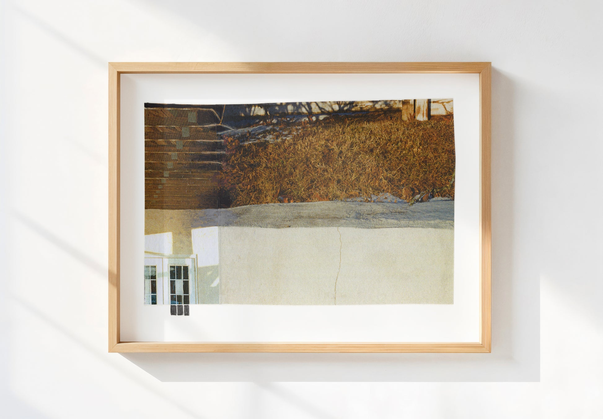 Photo collage with golden grass and a small window element in a wood frame.