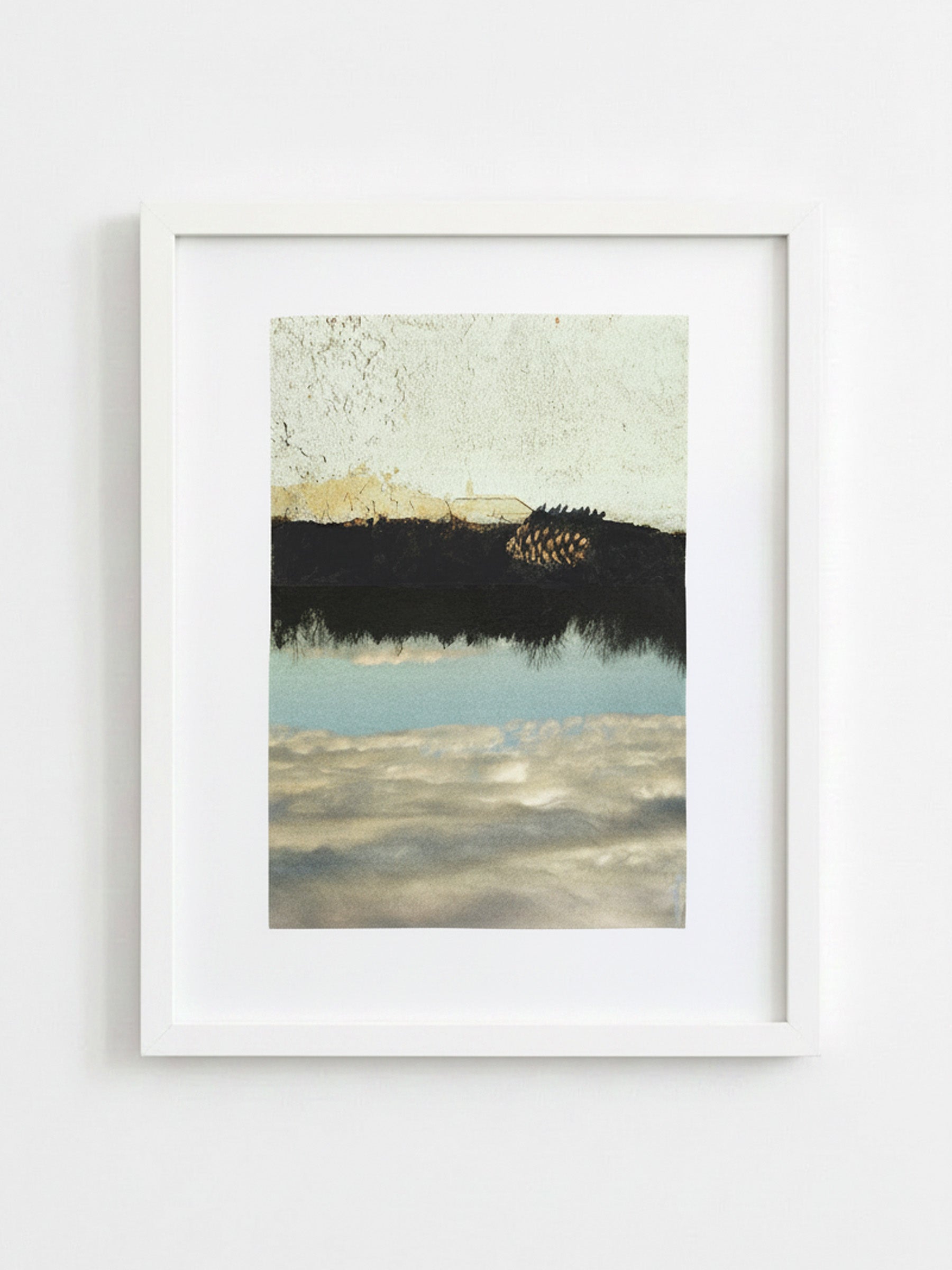 A framed abstract landscape art print featuring a textured cream sky, a dark black horizon, and a light blue reflective water section, housed in a white frame against a white wall.