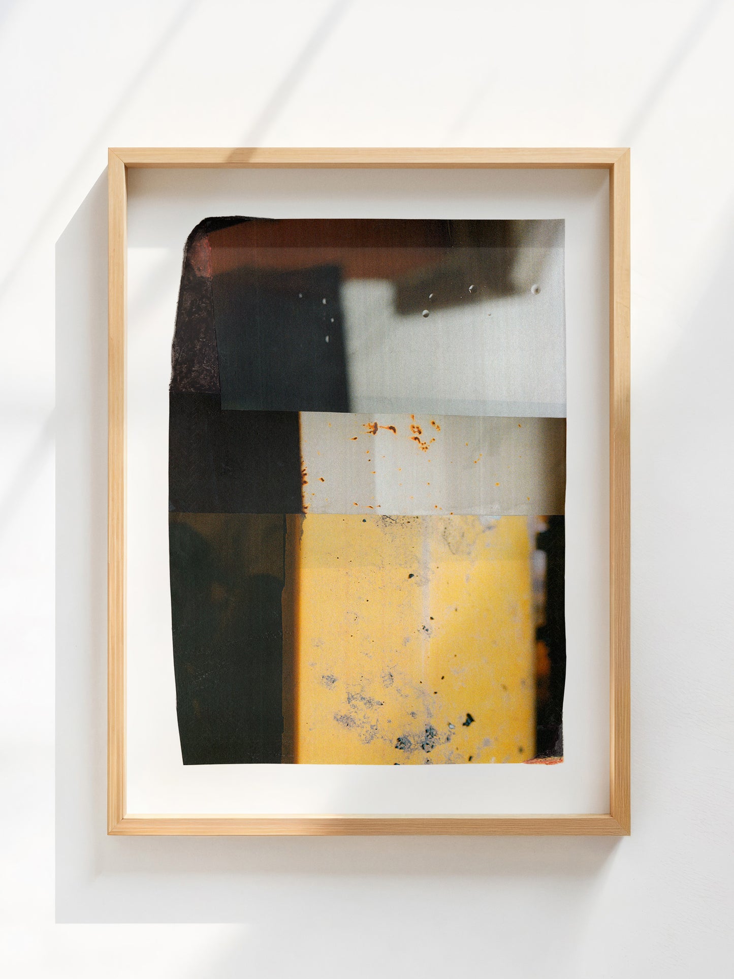 Abstract geometric art print with charcoal, cream, and golden yellow blocks in an oak frame.