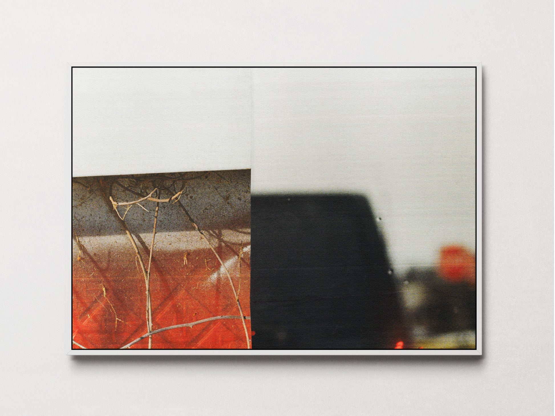 Framed abstract art print featuring a split composition with an orange and brown section on the left and a dark, blurry black shape on the right, displayed against a light gray wall.