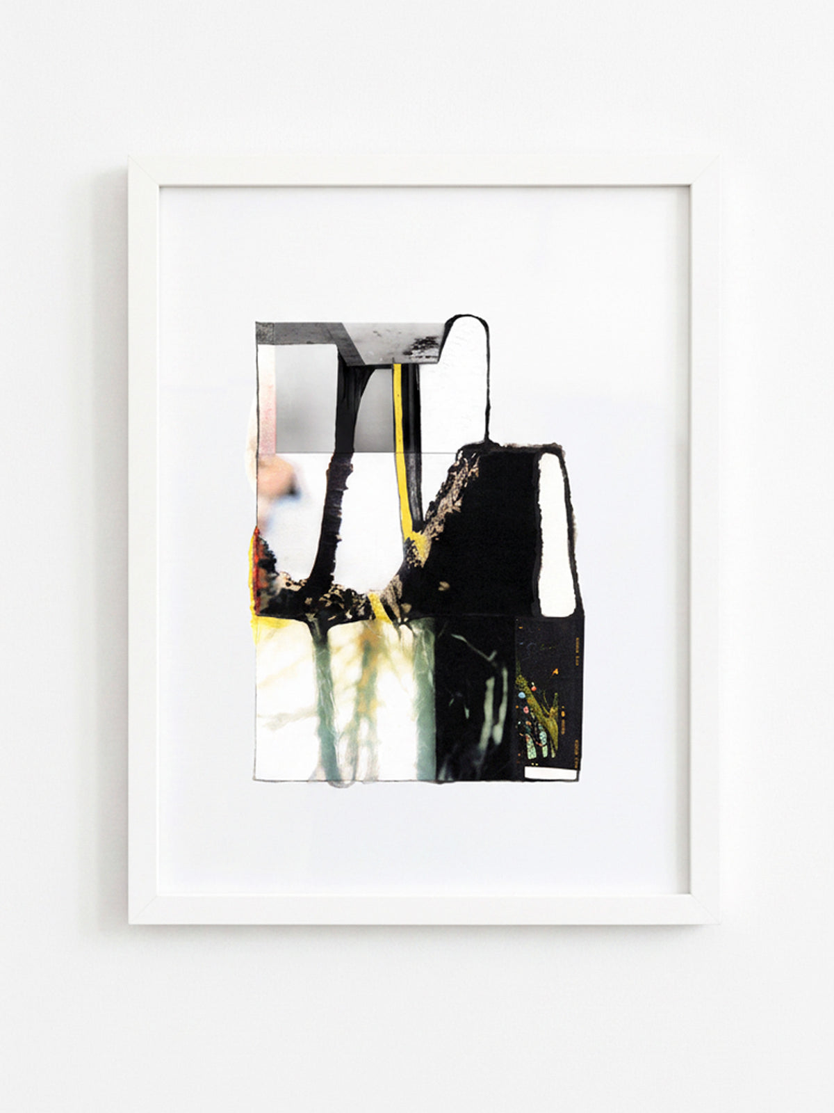 A framed abstract art print featuring black, white, gray, and yellow paint drips, presented in a white frame against a clean white wall.