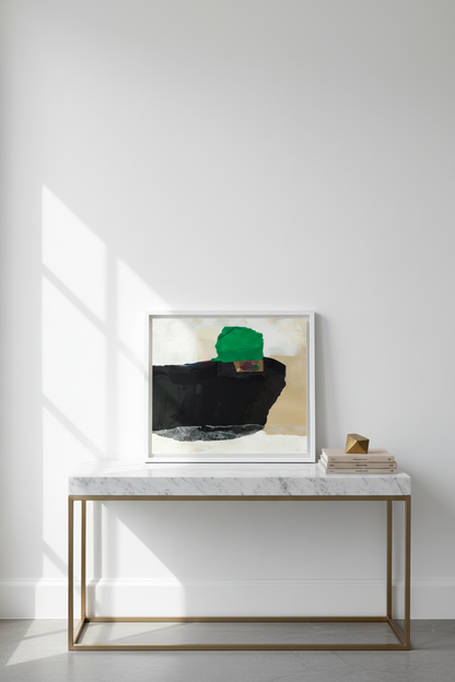 Abstract framed wall art with bold black, green, beige, and gray brushstrokes, displayed on a white marble console table with a gold metal frame in a bright, modern room.