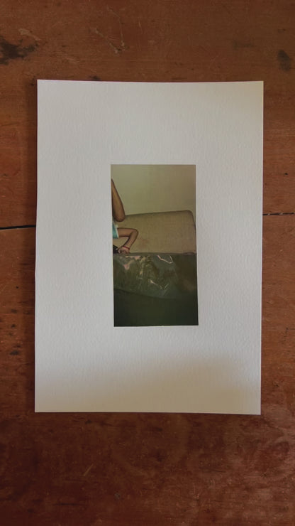 Photo collage artwork featuring a cropped image of a child's arm balancing on a couch while doing a headstand, combined with a dark, abstract photograph of a sun-dappled tarp. The piece contrasts domestic intimacy with organic texture, blending warm tones and muted greens.