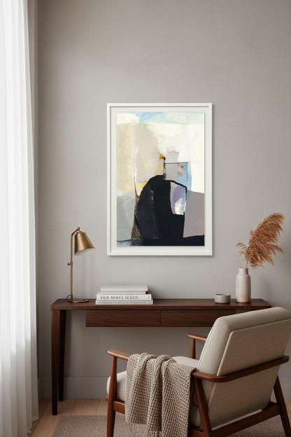 A framed abstract art print with a white frame hangs on a gray wall above a dark wood console table. The print features black, beige, and gray geometric shapes.